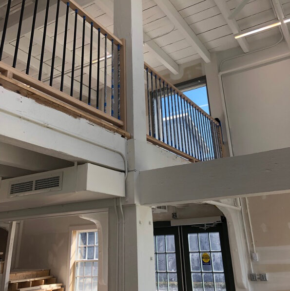 Interior of building showing ground floor, beams and second floor loft with railing